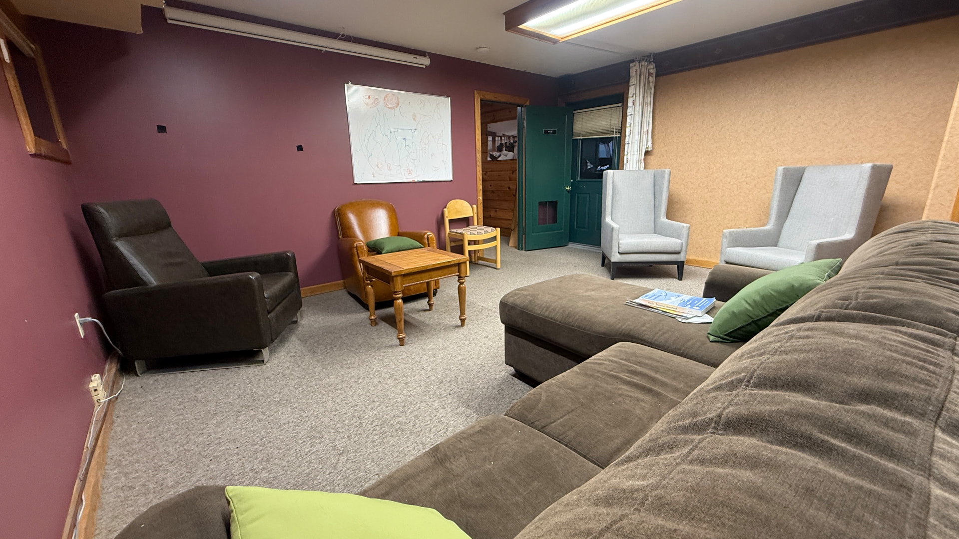 Second sitting room with sectional couch, armchairs and a whiteboard