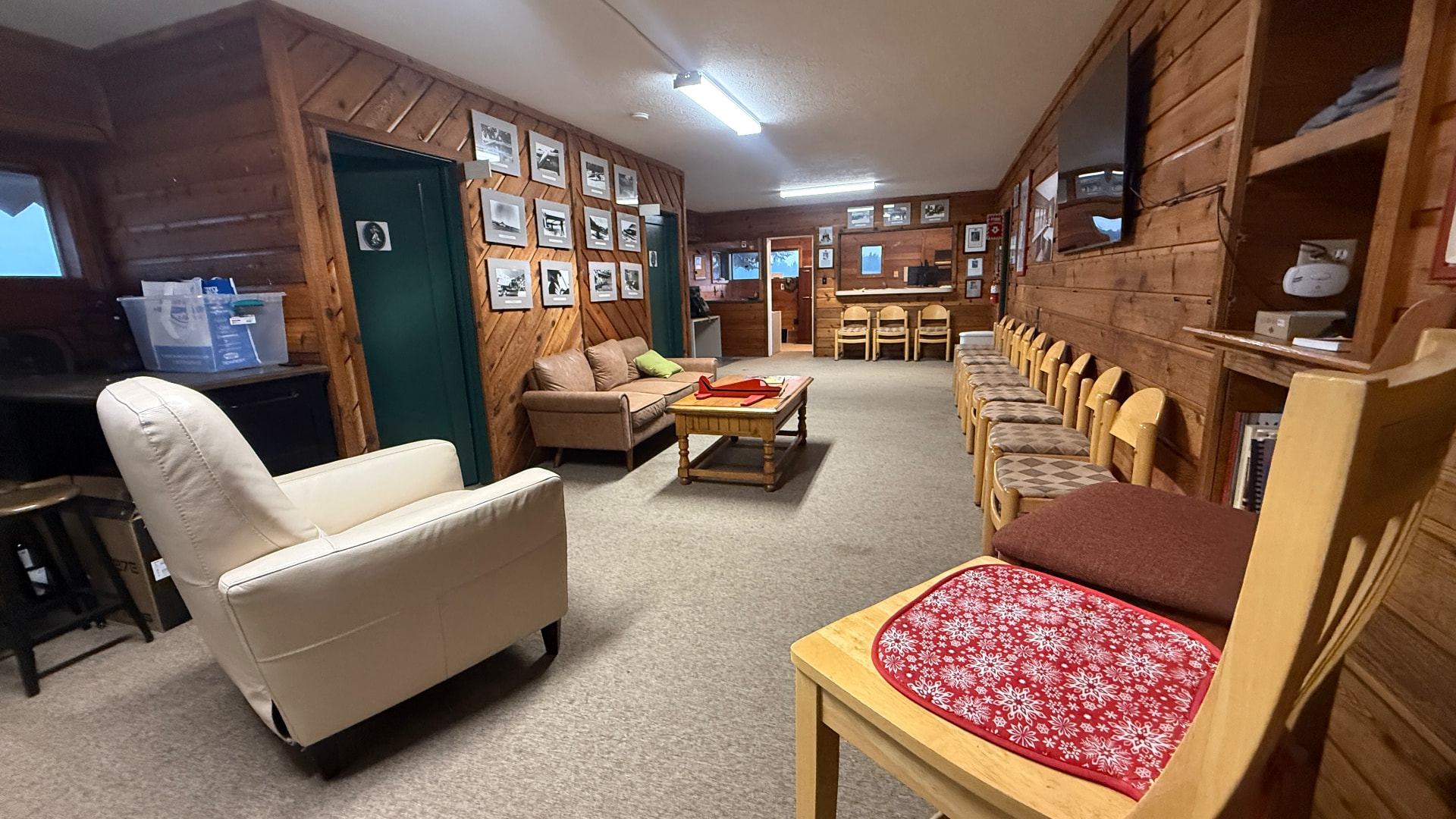 Hangar lounge with couches, armchairs, a coffee table and historic aviation photos on the wall