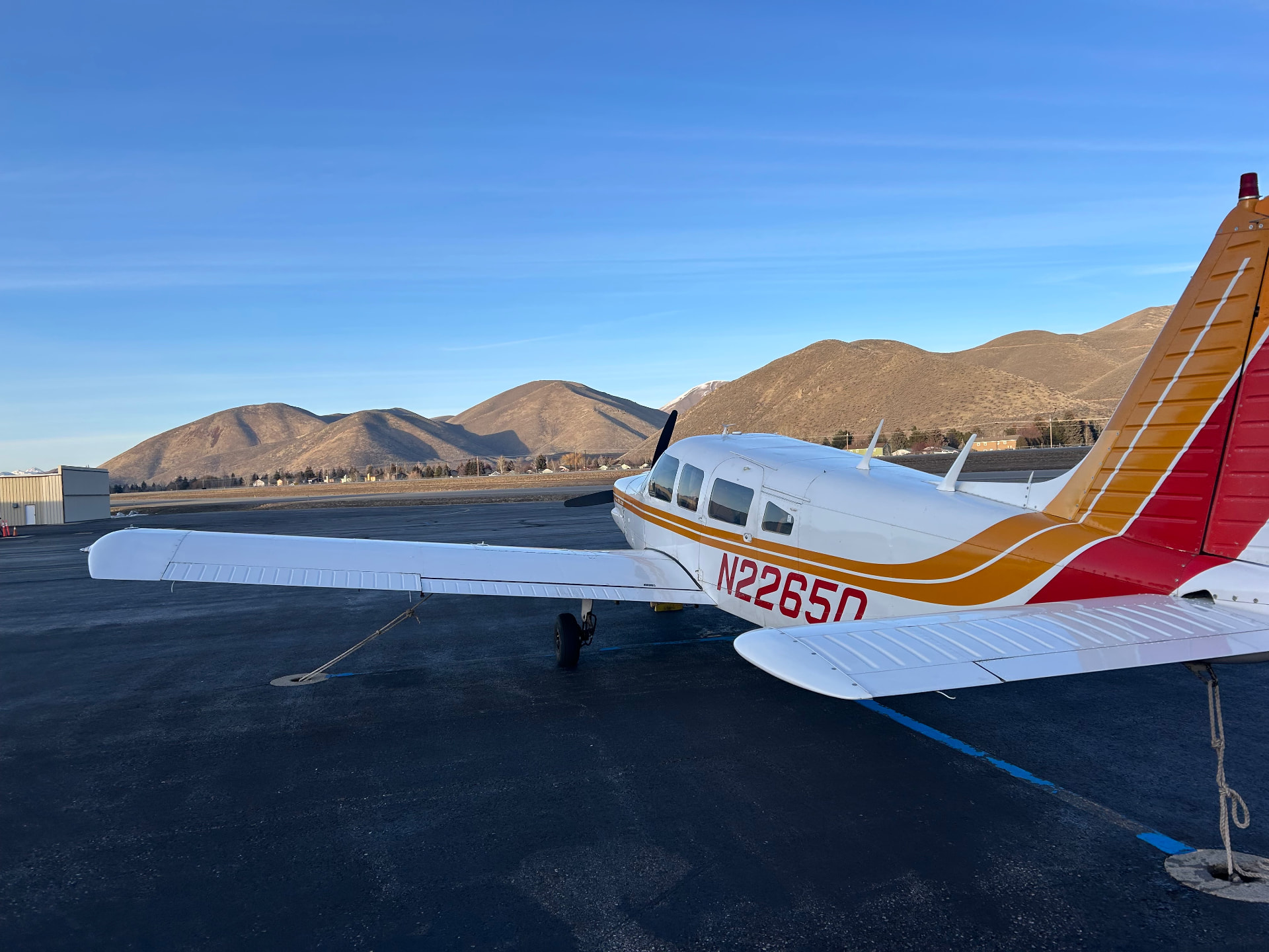 Piper Cherokee Six N2265Q tied down on the ramp with foothills behind